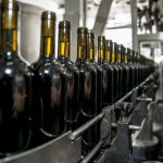Garrafas de vinho alinhadas em uma linha de produção industrial.