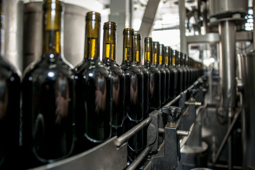 Garrafas de vinho alinhadas em uma linha de produção industrial.