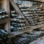Garrafas de vinho empoeiradas, com rolhas, armazenadas em prateleiras de madeira em uma propriedade vitivinícola