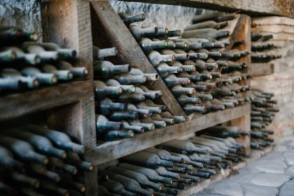 Garrafas de vinho empoeiradas, com rolhas, armazenadas em prateleiras de madeira em uma propriedade vitivinícola